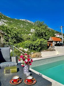 a table with two cups and a vase with flowers at Maison Laurel - Exquisitely Renovated Centuries Old Stone Estate With Private Pool, Near Split and Omiš in Gata