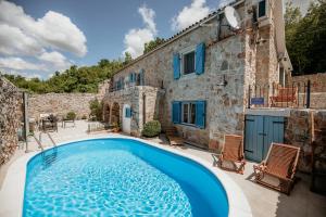 ein Haus mit einem Pool vor einem Gebäude in der Unterkunft Villa Toscana - Charming stone Villa with private pool & garden in Grižane