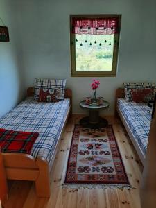 2 camas en una habitación con mesa y ventana en Kosta's romantic house, en Plav