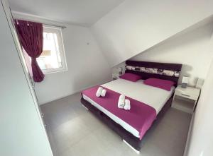 ein Schlafzimmer mit einem großen Bett mit violetter Bettwäsche in der Unterkunft Apartmani Agi in Budva