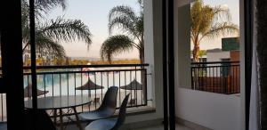 balcón con mesa, sillas y vistas a la piscina en Blyde Lagoon View Apartment, en Pretoria