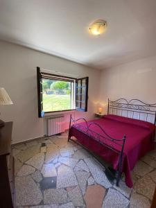 a bedroom with a red bed and a window at Casa di Campagna in Gallura in Luogosanto