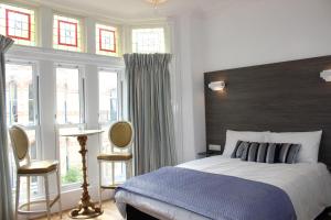 a bedroom with a bed with a blue blanket and windows at Grosvenor House - onsite free parking in Ilfracombe