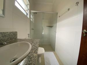 uma casa de banho branca com um lavatório e um chuveiro em Graal Inn Queluz em Queluz