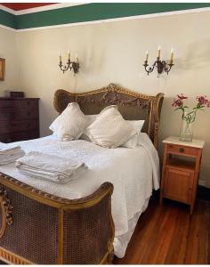 Una cama con sábanas blancas y almohadas en un dormitorio en Casa Wilson en Zapallar