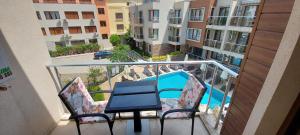 a balcony with a table and chairs and a swimming pool at Менада Хоризонт Апартаменти in Sozopol