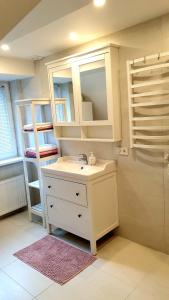 ein weißes Badezimmer mit einem Waschbecken und einem Spiegel in der Unterkunft KANTO - self check in in Klaipėda