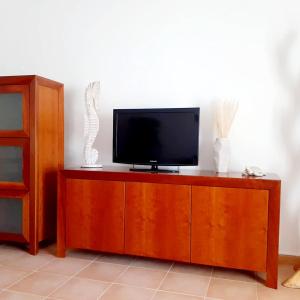 una TV a schermo piatto seduta sopra un armadio in legno di Casa Ocean a Carvoeiro