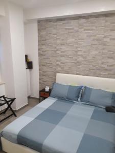 a bedroom with a blue bed and a brick wall at Maison Marguerite in Margherita di Savoia