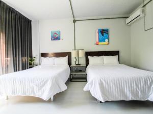 two beds in a hotel room with white sheets at VL Hotel Boutique by Rotamundos in Guadalajara