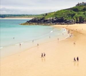 a group of people walking on a beach at Harbour View Guest House in St Ives