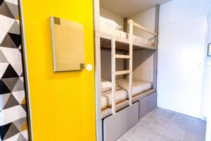Cette chambre dispose de lits superposés et de murs jaunes. dans l'établissement Beau Studio pour 4 personnes à Fréjus, à Fréjus