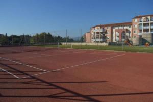 un court de tennis avec un bâtiment en arrière-plan dans l'établissement Beau Studio pour 4 personnes à Fréjus, à Fréjus