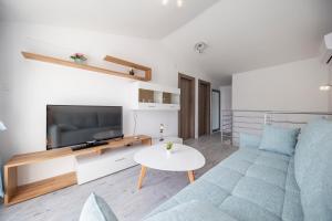 a living room with a blue couch and a tv at Apartments Haluga in Pag