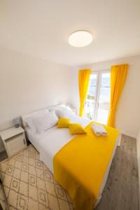 a bedroom with a large bed with yellow curtains at Apartments Haluga in Pag