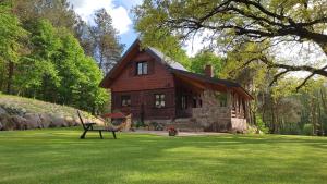 une maison en bois avec un banc dans l'herbe dans l'établissement DOMEK POD DĘBEM, à Mielnik