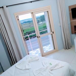 a bedroom with a bed and a large window at Pousada Aparados in Cambara do Sul