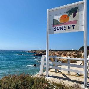 a sign on the beach next to the ocean at Sunset Studios & Rooms in Antiparos