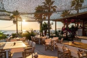 un restaurante en la playa con mesas y sillas en Sunset Studios & Rooms, en Antíparos