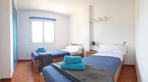 Dos camas en una habitación con toallas azules. en Apartamentos Loremar, en Portocolom