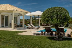 a patio with chairs and an umbrella next to a pool at Villa Evanna in Lefkimmi