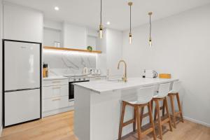 a kitchen with white appliances and a counter with stools at Stay Coastal - Mission Bay in Auckland