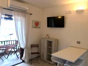 a living room with a table and a tv on the wall at Charme House Palau in Palau