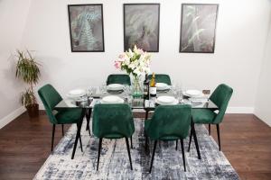 a dining room with a table and green chairs at High Life Serviced Apartments - Old Town in Swindon