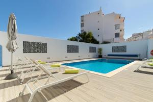 a swimming pool with lounge chairs and a building at Villa Tropicana in Albufeira