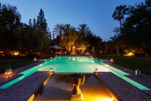 una piscina por la noche con luces encendidas en Dar Ayniwen Garden Hotel & Bird Zoo, en Marrakech
