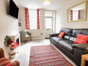 a living room with a leather couch and a television at 6 Smithfield Lane in Dolgellau