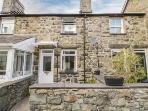 a stone house with a white door and windows at 6 Smithfield Lane in Dolgellau