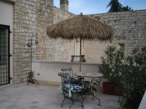 eine Terrasse mit einem Tisch, Stühlen und einem Strohschirm in der Unterkunft Casarosa B&B de Charme in Cassano delle Murge