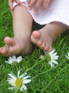 Ein kleines Mädchen steht im Gras mit weißen Blumen in der Unterkunft Bauernhof Pergila in Maria Luggau