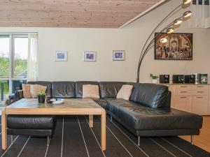 Loddenhøjにある12 person holiday home in Aabenraaのリビングルーム(黒い革張りのソファ、テーブル付)