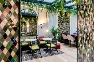 ein Restaurant mit Tischen, Stühlen und Pflanzen in der Unterkunft Best Western Plus Crystal, Hotel,Bar & Spa in Nancy