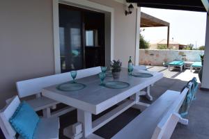 uma mesa branca e cadeiras num pátio em Dreamcatcher villa: Infinity pool, Sunset, Seaview em Agios Leon