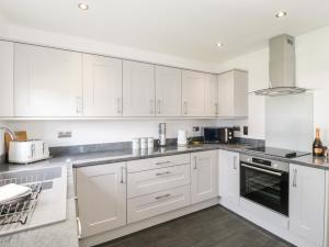 a white kitchen with white cabinets and appliances at 3 Parc Delfryn in Brynteg