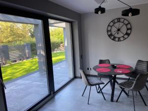 a dining room with a table and chairs and a clock at Boszkowo Makowa Cisza in Boszkowo