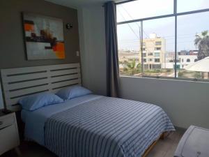 a bedroom with a bed and a large window at Hospedaje Nuna - Playa Huanchaco in Huanchaco