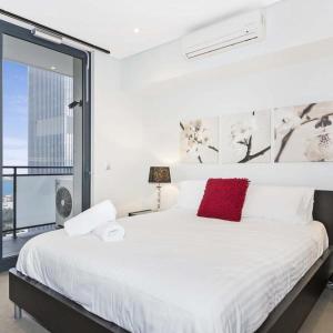 a bedroom with a large white bed with a red pillow at Astra Apartments Perth - Zenith in Perth