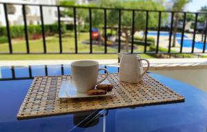 two coffee cups and donuts on a table on a balcony at Apartamento en la Torre Golf Resort in Torre-Pacheco