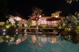 a swimming pool at night with an umbrella at Puri Andong Villa in Ubud