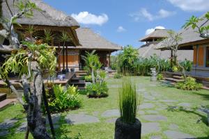 a resort with a garden with palm trees at Puri Andong Villa in Ubud