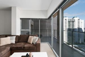 a living room with a couch and a large window at Astra Apartments Perth CBD in Perth