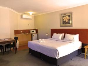 a hotel room with a large bed and a table at Higgins Lane Motel in Margaret River Town