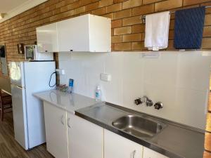a kitchen with a sink and a refrigerator at Shelly Beach Motel in Hervey Bay