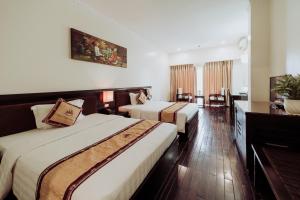 White Palace Thai Binh Hotel في Thái Bình: غرفه فندقيه سريرين وتلفزيون