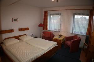 a bedroom with a bed and a table and chairs at Hotel garni Zur Post in Utersum