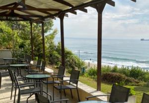 a patio with tables and chairs and the ocean at Family Hotel Albizia Beach in Varna City
